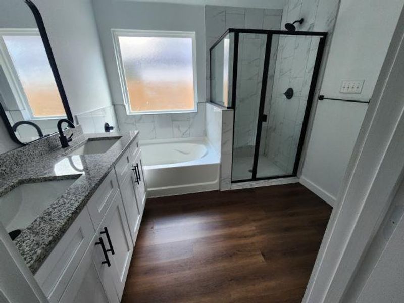 Full bath with a garden tub, a marble finish shower, double vanity, and dark wood-style floors Full bath with a garden tub, a marble finish shower, double vanity, and dark wood-style floors