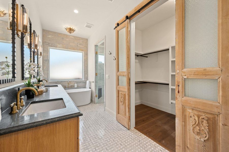 Bathroom with a stall shower, double vanity, a freestanding bath, a spacious closet, and light tile patterned floors