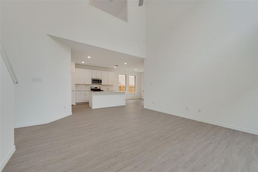 Unfurnished living room featuring a towering ceiling and light hardwood / wood-style floors