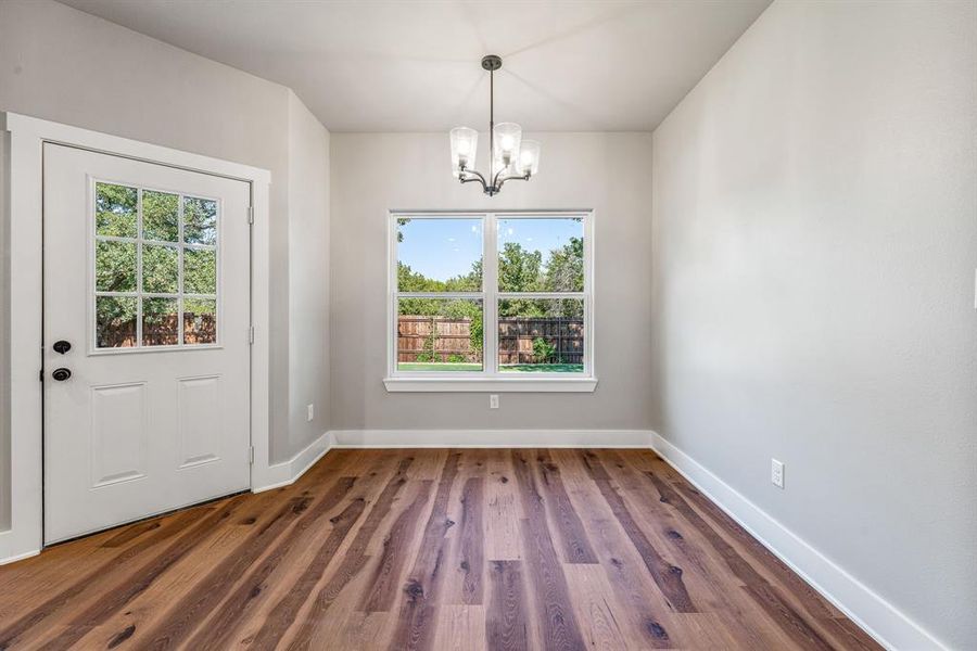 Unfurnished dining area with dark wood-type flooring and a chandelier Unfurnished dining area with dark wood-type flooring and a chandelier
