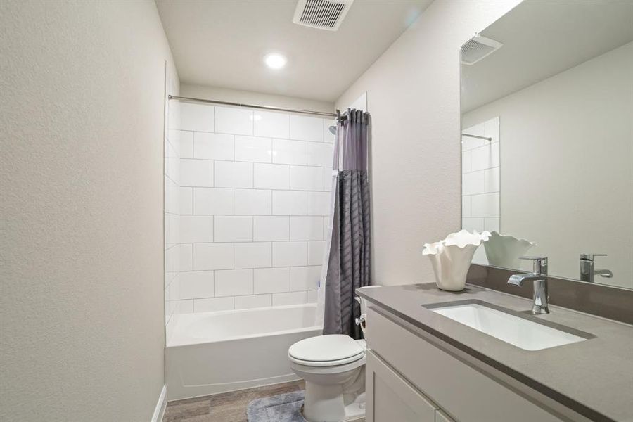 Full bath featuring vanity, light wood-style flooring, and shower / bath combo with shower curtain Full bath featuring vanity, light wood-style flooring, and shower / bath combo with shower curtain