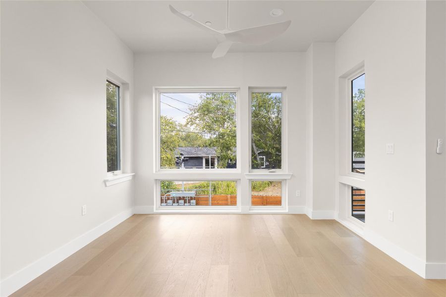 Sunlight streams through large windows onto smooth hardwood flooring in this versatile living space.