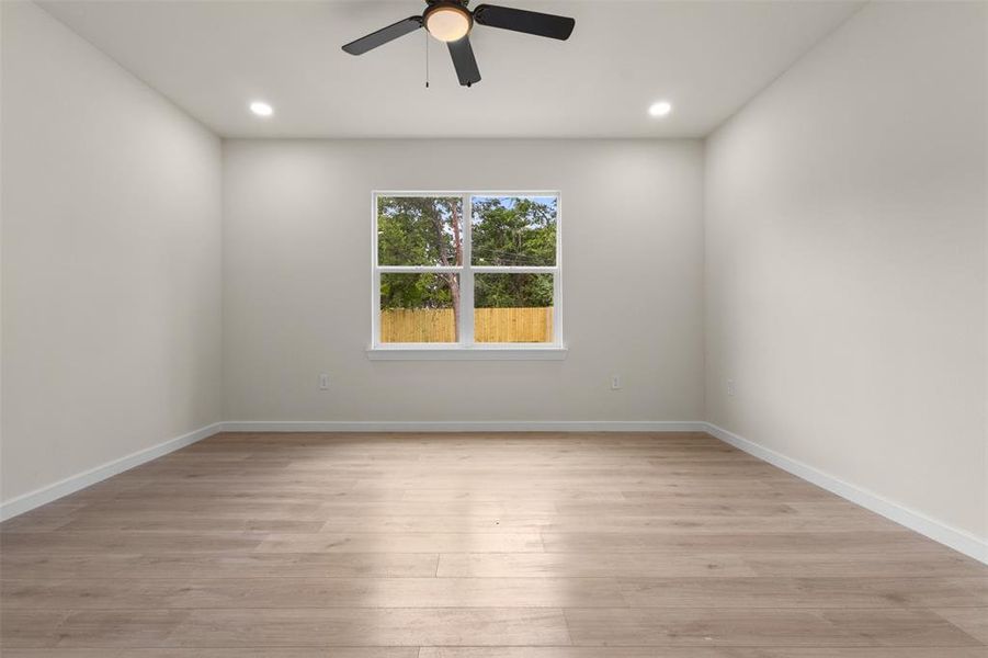Bright room featuring wood-finish flooring, a ceiling fan with integrated lighting, and recessed ceiling lights