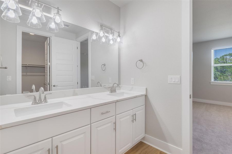 Primary bath featuring dual vanity, quartz countertops, modern fixtures, large walk in closet, and floor-to-ceiling shower tile Primary bath featuring dual vanity, quartz countertops, modern fixtures, large walk in closet, and floor-to-ceiling shower tile