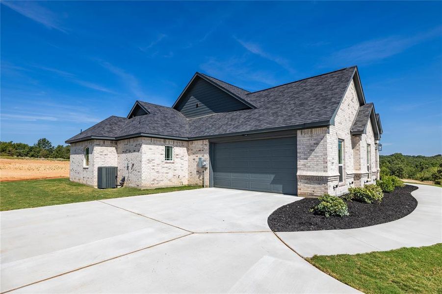 View of front facade with a front yard, a garage, and central AC