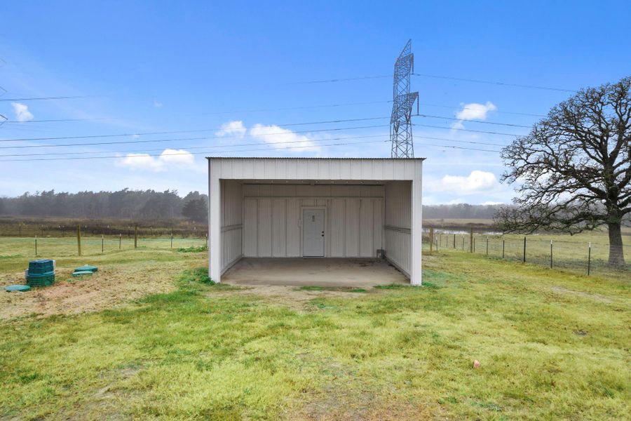 An expansive open-front shed with a finished concrete floor provides protected storage for vehicles, ATVs, or trailers.