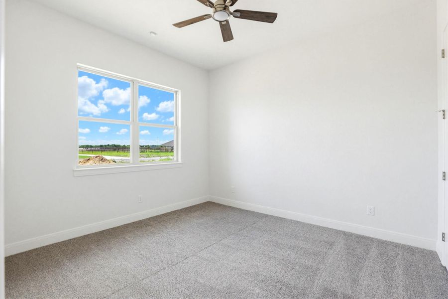 A well-lit bedroom features plush carpeting and a large window offering natural light.
