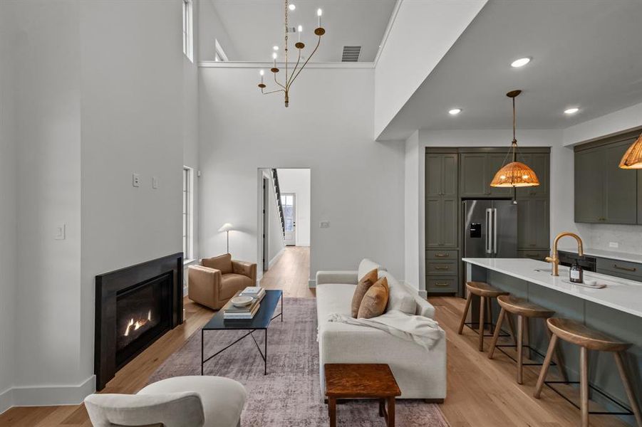 Living room featuring sink, a high ceiling, and light wood-type flooring