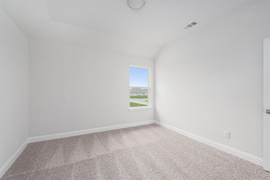 Spare room with lofted ceiling, carpet floors, visible vents, and baseboards