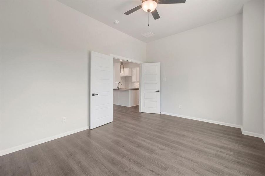 Spacious room featuring gray wood-finish flooring and a contemporary ceiling fan with integrated lighting Spacious room featuring gray wood-finish flooring and a contemporary ceiling fan with integrated lighting