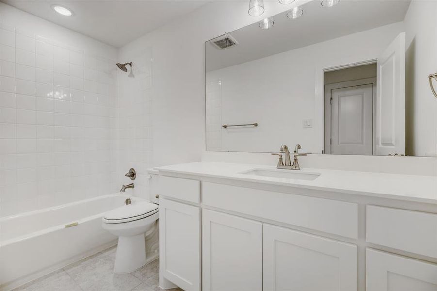Bathroom featuring a white vanity with an integrated sink, brushed nickel faucet, and a large mirror