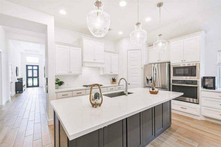 Quartz counters, plenty of storage space, pendant lighting, and stainless appliances highlight this kitchen. Quartz counters, plenty of storage space, pendant lighting, and stainless appliances highlight this kitchen.