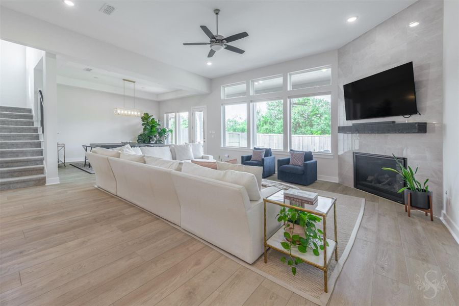 The expansive family room is centered around a dramatic floor-to-ceiling tiled fireplace with a striking floating mantel. A wall of windows fills the space with natural light and showcases views of the backyard. The expansive family room is centered around a dramatic floor-to-ceiling tiled fireplace with a striking floating mantel. A wall of windows fills the space with natural light and showcases views of the backyard.