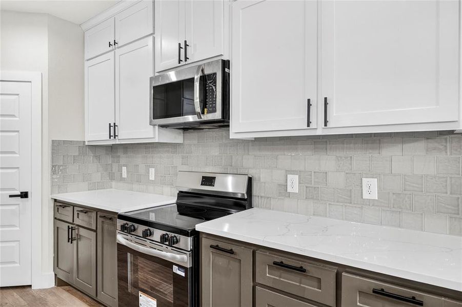 Modern kitchen featuring a central island with an undermount sink, white countertops, and wood-finish flooring