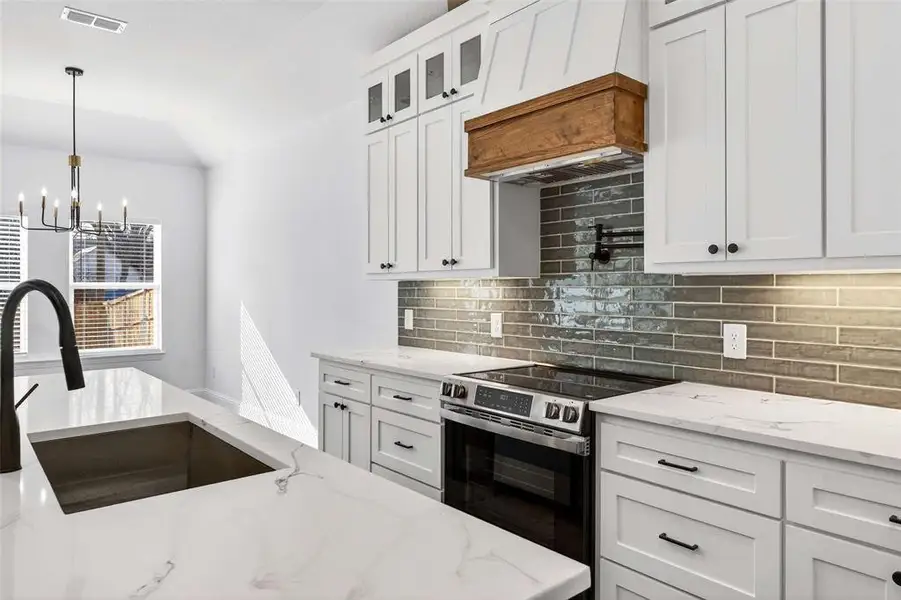 Kitchen featuring white cabinets, stainless steel range with electric stovetop, and light stone counters