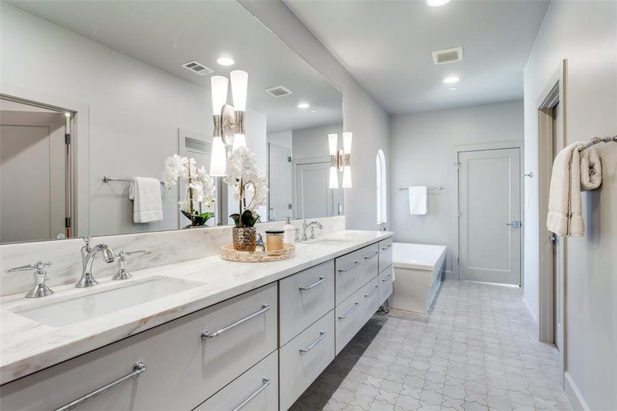 Bathroom with double vanity, tile patterned flooring, and a bath