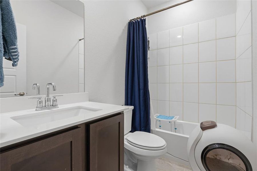 Bathroom featuring a white vanity countertop with an integrated sink, dark wood-finish cabinetry, chrome fixtures, and a tiled shower/tub combination