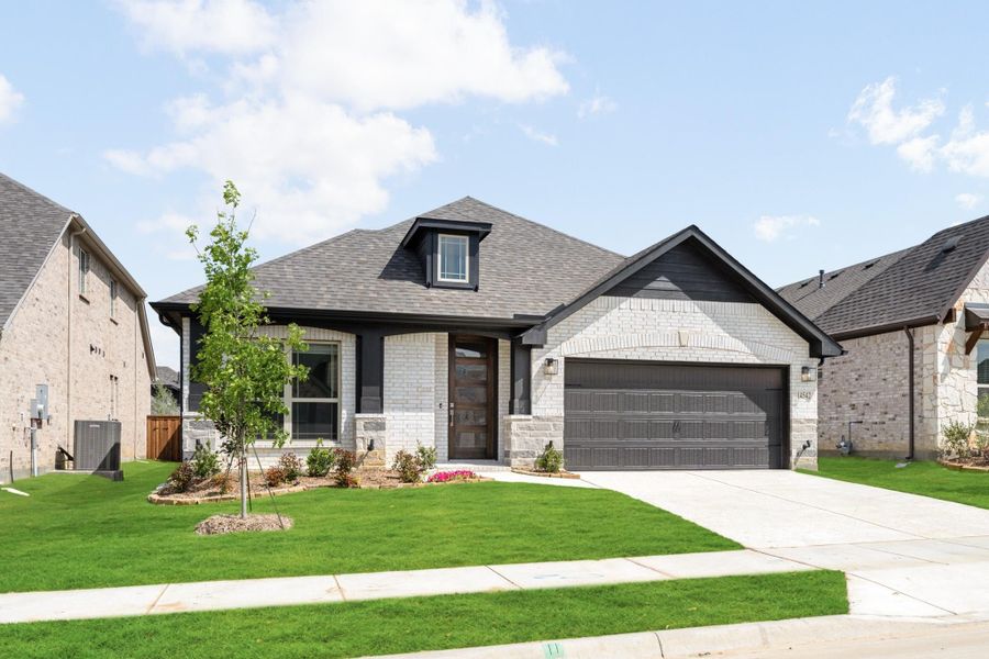 Single-story home with white brick exterior, two-car garage, and manicured front lawn