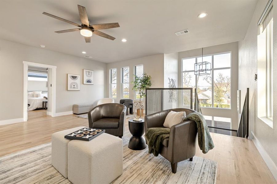 Living room featuring light hardwood / wood-style floors, plenty of natural light, and ceiling fan with notable chandelier