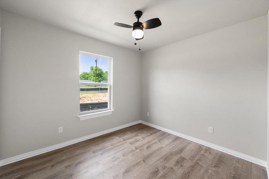 Room featuring wood-finish flooring, a ceiling fan with integrated lighting, a single window, white baseboards, and light-toned wall finishes