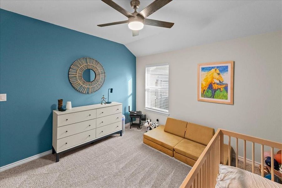 Carpeted bedroom with a ceiling fan and vaulted ceiling