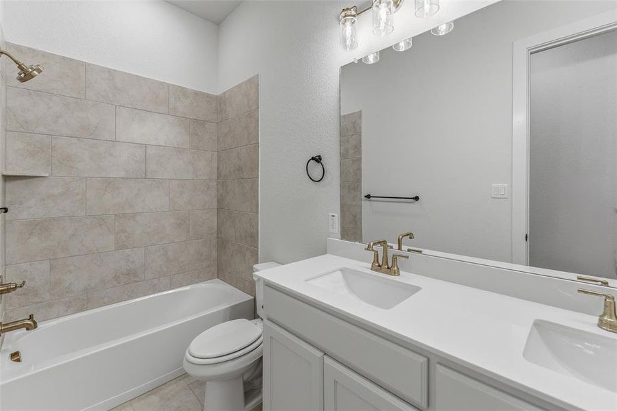 Full bathroom featuring a dual vanity with white cabinetry and integrated sinks, complemented by a large mirror and five-light vanity fixture Full bathroom featuring a dual vanity with white cabinetry and integrated sinks, complemented by a large mirror and five-light vanity fixture