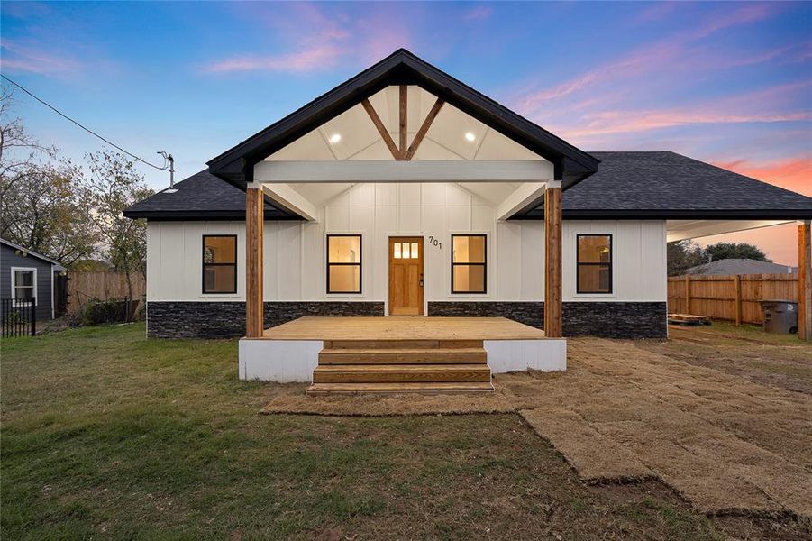 Back house at dusk featuring a lawn and a wooden deck