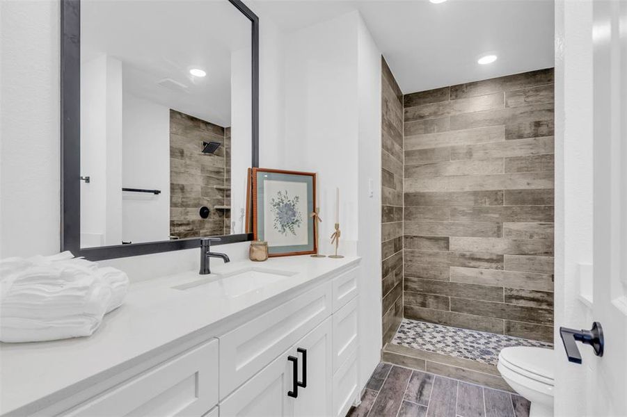 Bathroom featuring vanity, a tile shower, recessed lighting, and wood finished floors