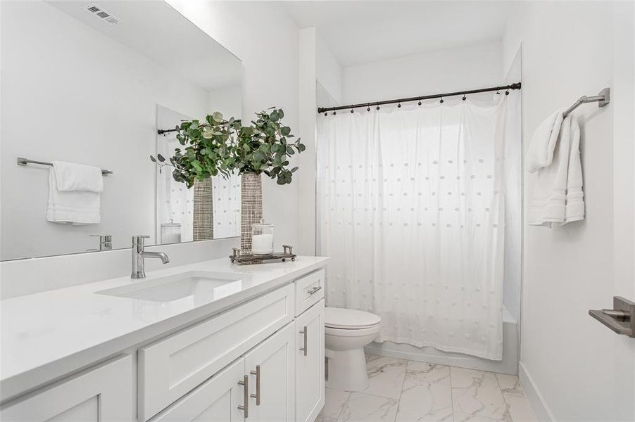 Full bathroom featuring tile patterned floors, shower / bath combo, toilet, and vanity