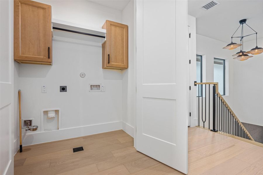 The laundry room is thoughtfully appointed with storage shelves, hanging rods, and both electric and gas dryer connections for modern convenience