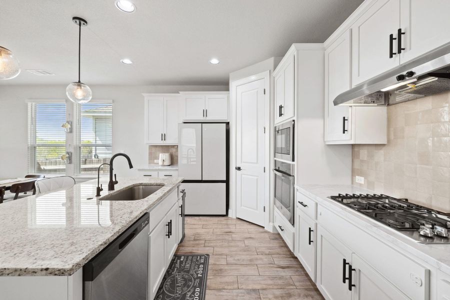 Kitchen featuring white cabinets, under cabinet range hood, a sink, and stainless steel appliances Kitchen featuring white cabinets, under cabinet range hood, a sink, and stainless steel appliances
