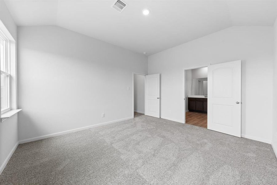 Bedroom with multiple windows, vaulted ceiling, and wood-style floors