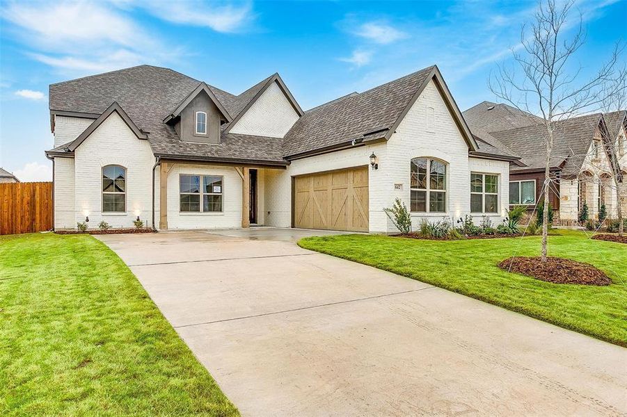 French country inspired facade with a garage and a front yard