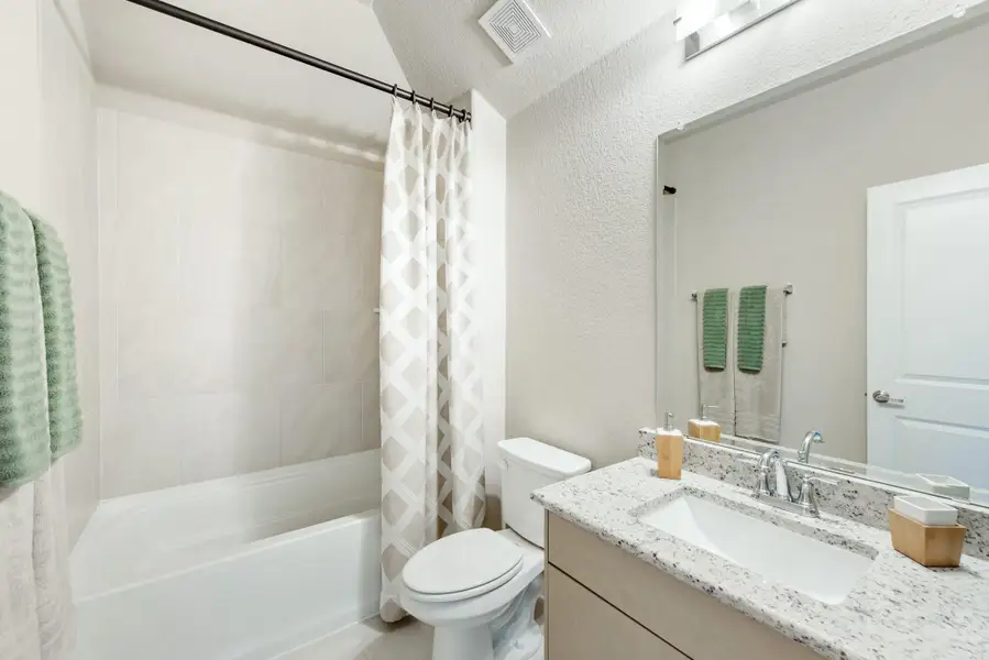 Full bathroom with granite countertop vanity, tub-shower combo with curtain, and toilet Full bathroom with granite countertop vanity, tub-shower combo with curtain, and toilet