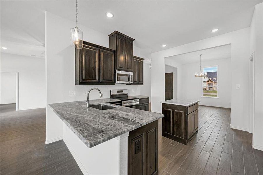 Kitchen featuring appliances with stainless steel finishes, sink, a kitchen island, and pendant lighting