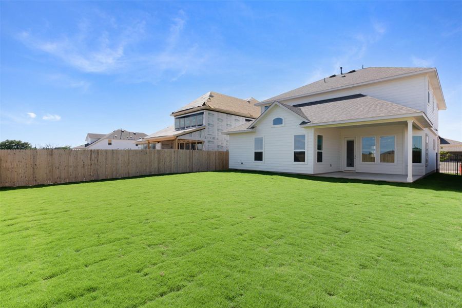 A generous backyard offers a verdant lawn and a charming covered patio for outdoor enjoyment.
