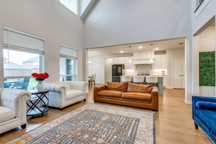 Living room with a towering ceiling and light hardwood / wood-style flooring