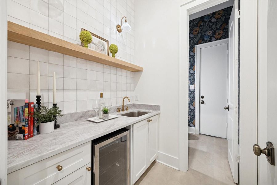 Functional butler’s pantry with Taj Mahal counters, undermount sink, open shelving, and a beverage cooler.