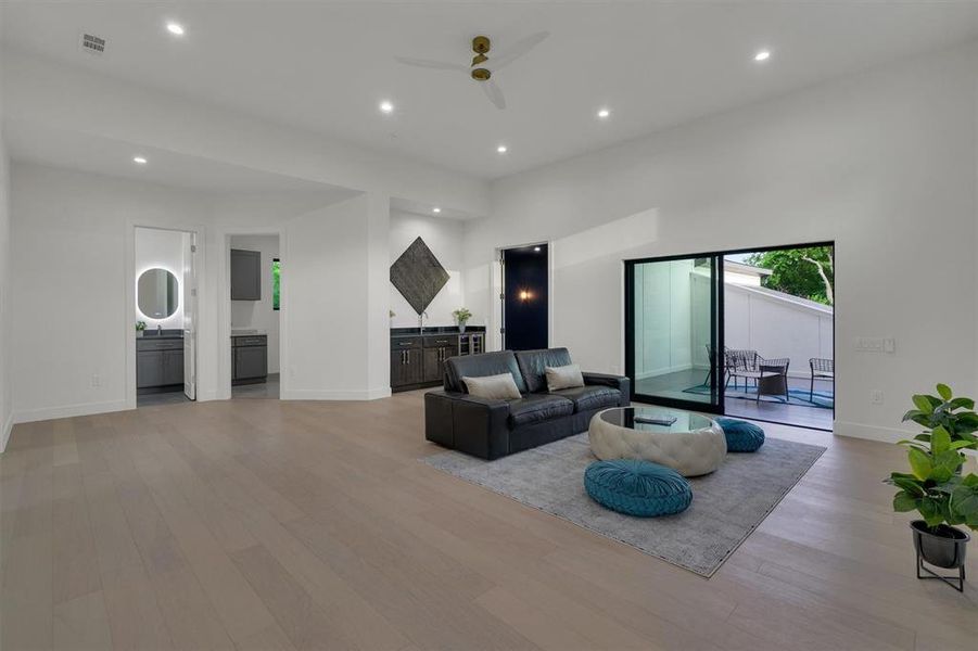 Living room with a high ceiling, light hardwood / wood-style floors, and ceiling fan