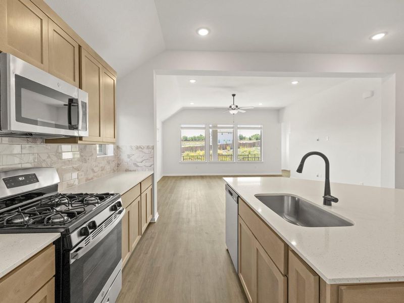 Kitchen featuring wood cabinetry, stainless steel appliances, light-toned countertops, and a subway tile backsplash