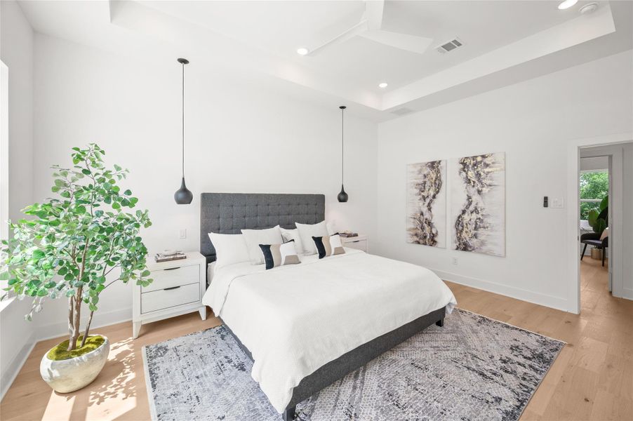 This spacious primary suite feels like a private retreat, featuring soaring tray ceilings, designer pendant lighting, and a calm atmosphere.