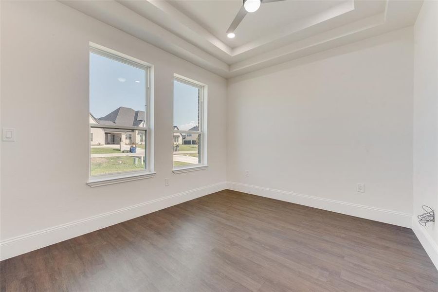 Bright interior featuring wood-finish flooring, two large windows, and a modern ceiling fan with integrated lighting Bright interior featuring wood-finish flooring, two large windows, and a modern ceiling fan with integrated lighting