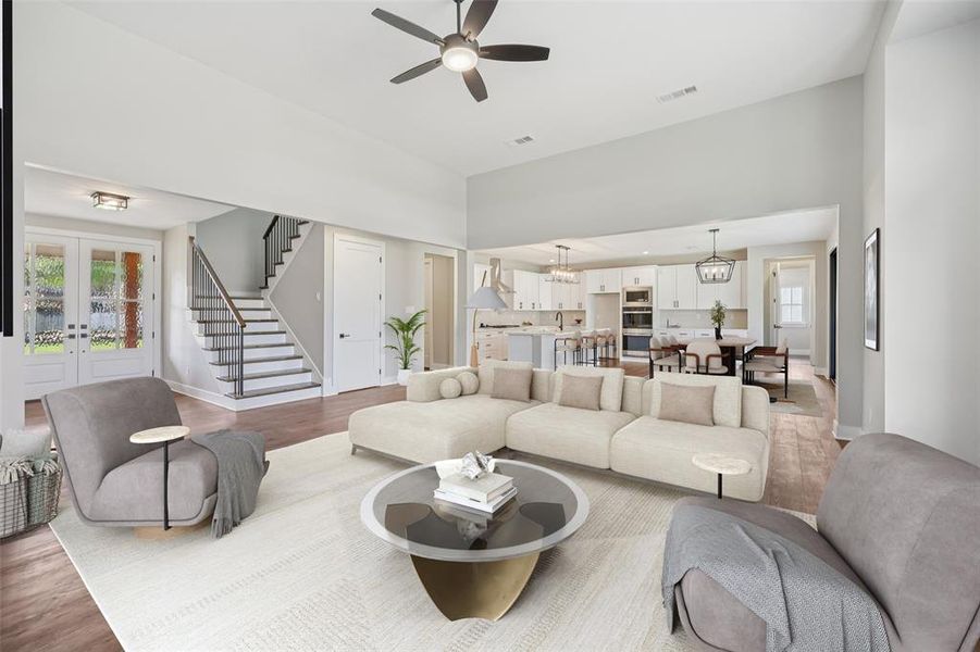 Living room with stairs, wood finished floors, french doors, a ceiling fan, and a chandelier