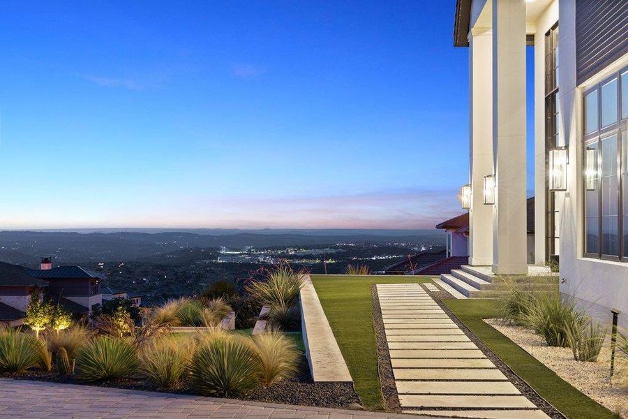 Columned entrance and tiered landscaping frame sweeping evening vistas from this elevated estate.