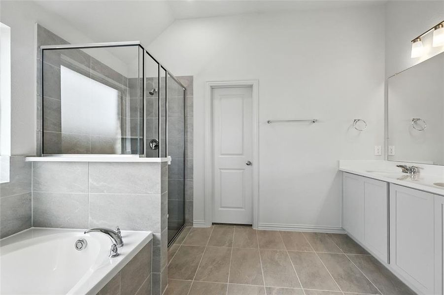Full bathroom featuring double vanity, a garden tub, and a stall shower Full bathroom featuring double vanity, a garden tub, and a stall shower