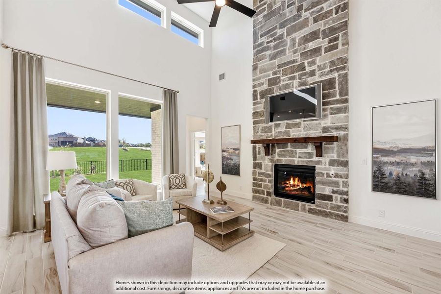 Living room with two-story stone fireplace, wood mantel, hardwood floors, and large windows with backyard view. Living room with two-story stone fireplace, wood mantel, hardwood floors, and large windows with backyard view.