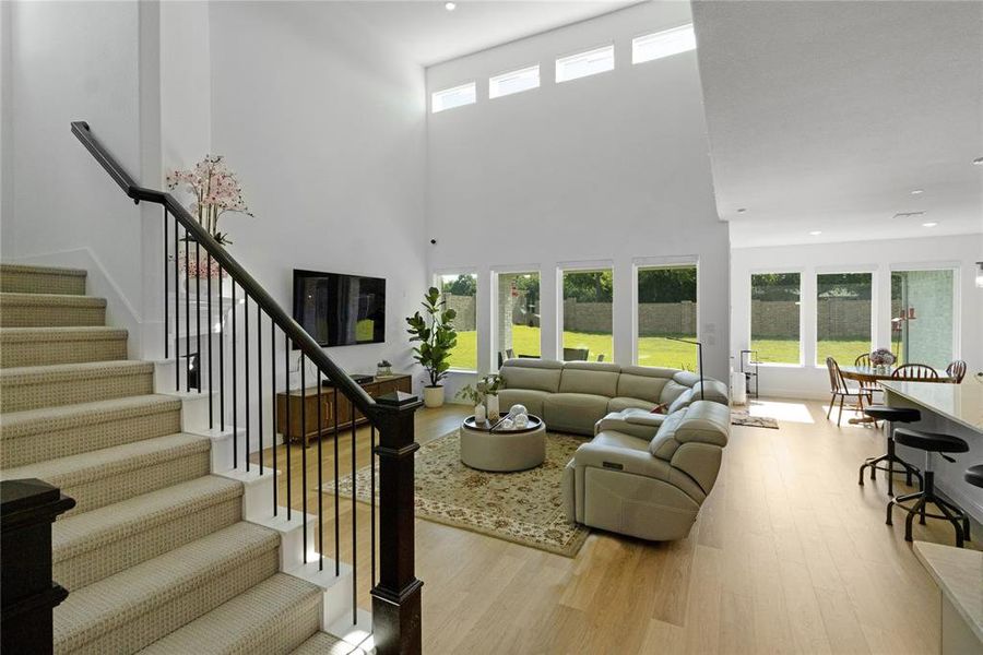 Two-story living area with high ceilings, upper transom windows, and expansive floor-to-ceiling windows overlooking the backyard