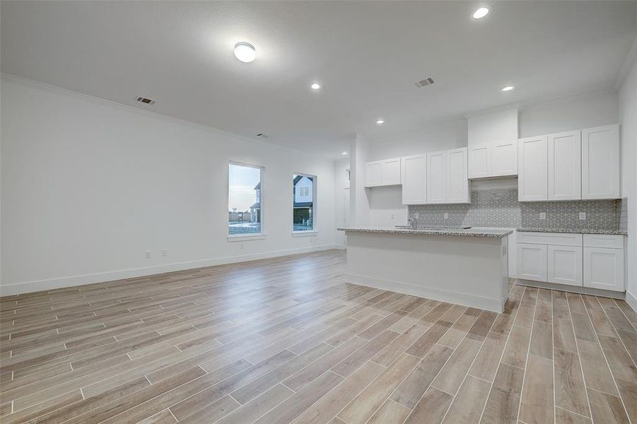 Alternate view of the large living space. A gray mosaic backsplash goes hand-in-hand with expansive granite countertops and white cabinetry.