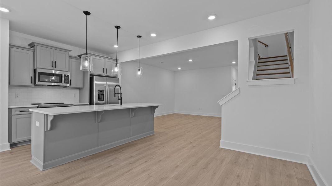 Highly skilled kitchen design includes a 9-foot island, quartz countertops, and stylish pendant fixtures