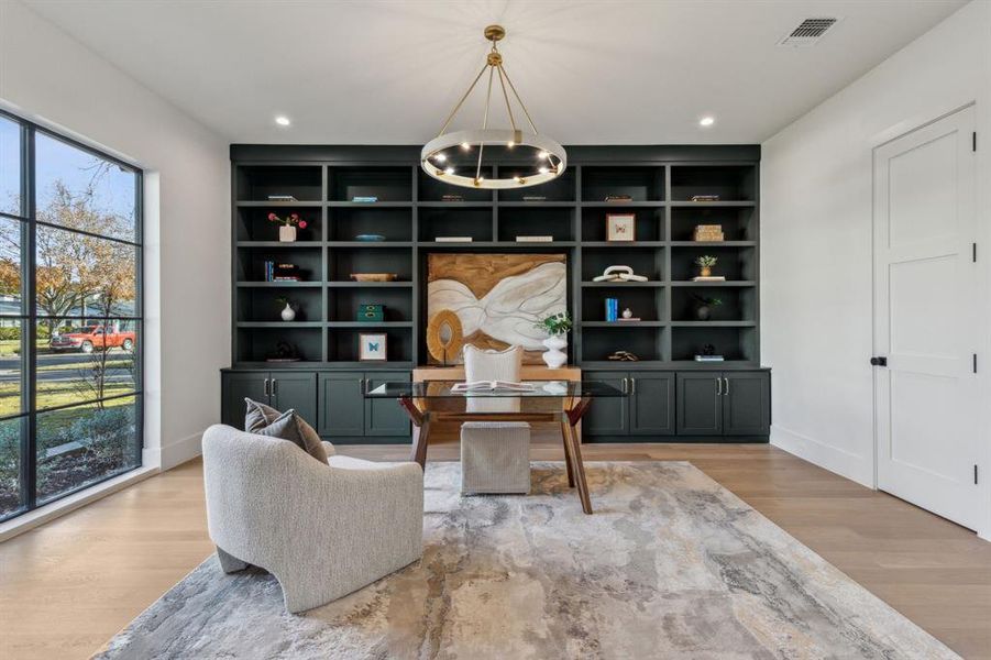 Sitting room featuring built in shelves, a wealth of natural light, and light hardwood / wood-style floors